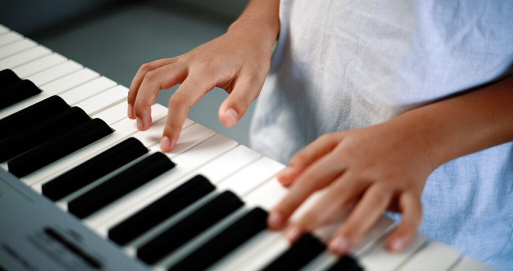 Image of kid playing the keyboard